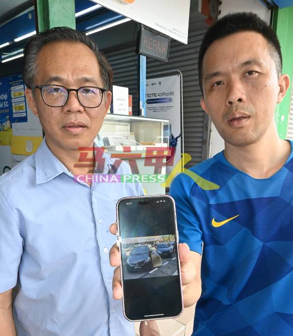 雷宝进（右）向刘志俍出示3年前广告牌掉落在两车之间的照片。