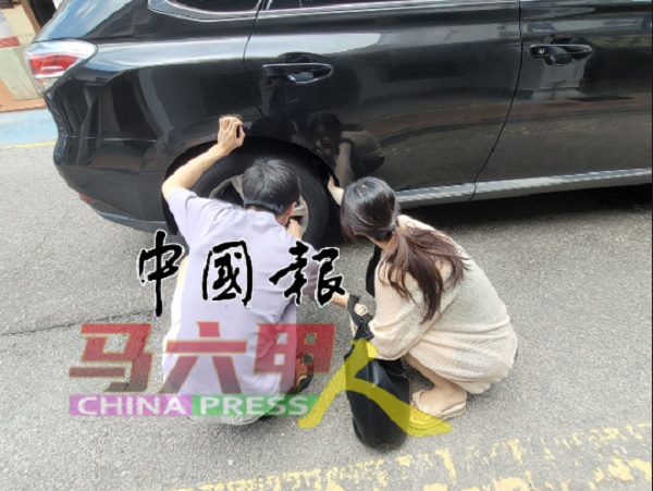 华裔青年男女发现猫咪走入车底，随后在后轮胎的后方发现猫咪踪影。