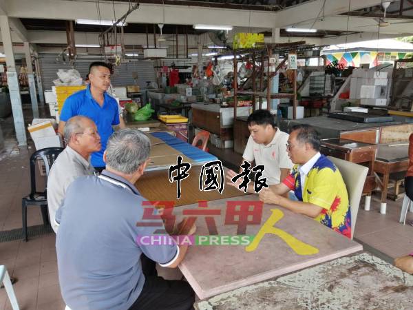 刘志俍（右）与小贩交流和传达讯息。