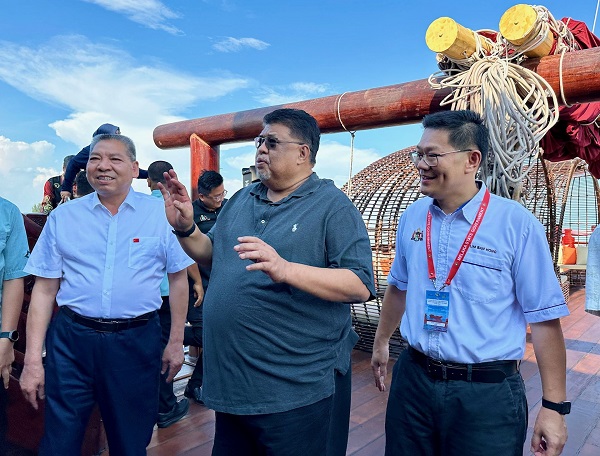 林万锋（右）陪同阿都拉勿参观停泊在马六甲港口的仿古木帆船福宁号。 左是船主林昌救。