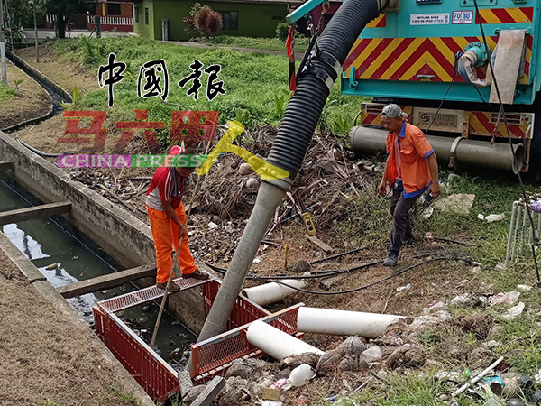 清沟工人用机器抽取甘榜帆加南马班底排水沟的垃圾，避免垃圾堵塞，影响排水的顺畅。