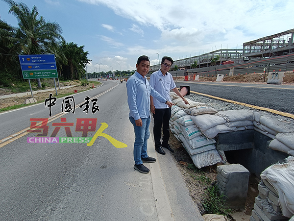 林重健（左起）向赖天斌指地势较低的道路将填高约2尺，以解决逢雨必灾的情况。