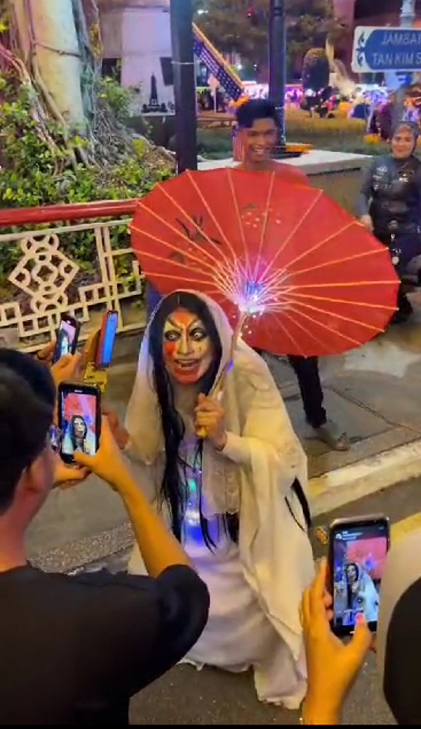 ■莫哈末赛分装扮成马来民间传说的“吸血女鬼”，娱乐游客。