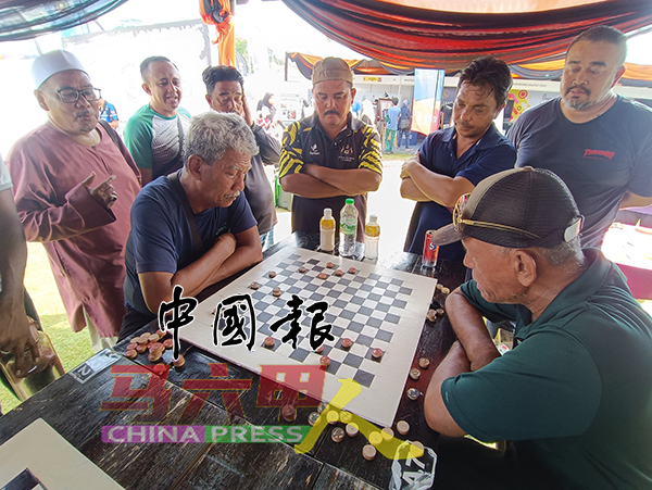 友族利用象棋棋子下黑白棋，在旁的伙伴看得津津有味。