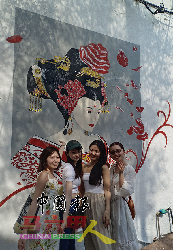 来自日本的游客，趁访问马六甲时，与范冰冰的壁画合照。
