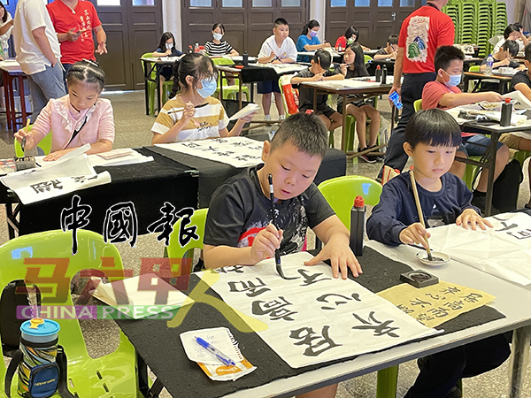 ■小学生在第18届“三山九九．重阳登高”书法赛上，全神贯注挥毫。