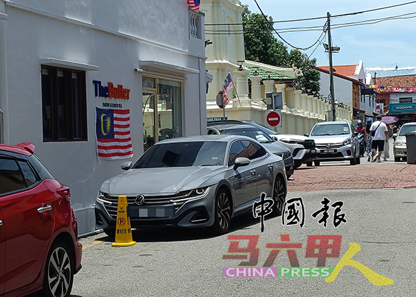 在老街，店家已设置交通锥提醒禁止泊车，该路段也属于禁泊区，遗憾有关车主依然将车泊于此，阻碍交通。