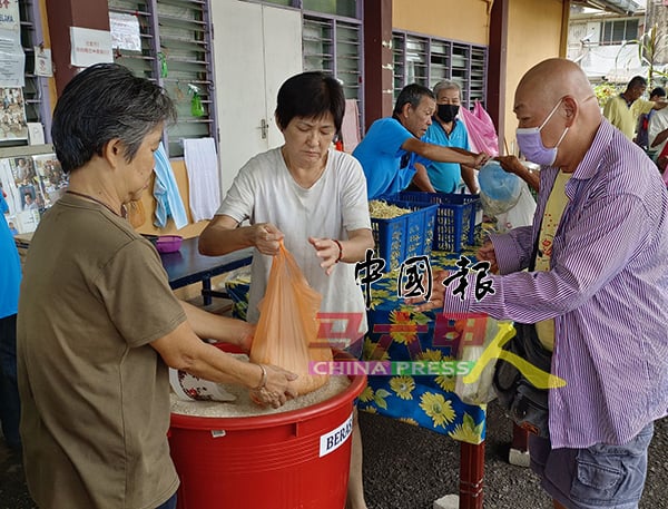 ■长者自备塑料袋，装白米带回家。