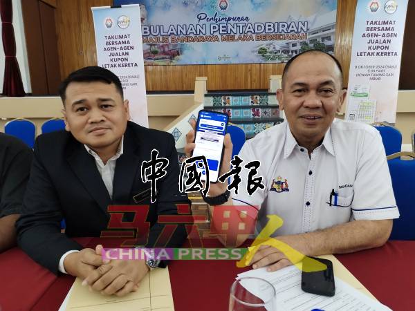 沙丹（右）展示Melaka Smart Parking手机应用程式；左为市政厅秘书阿末阿兹兰。