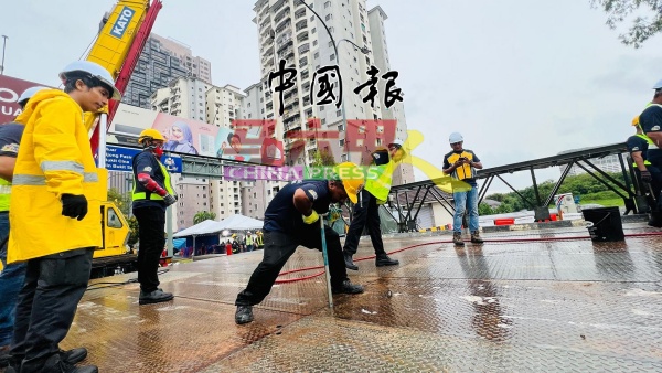 工作团队冒着与，在雨中完成倍力桥的安装。