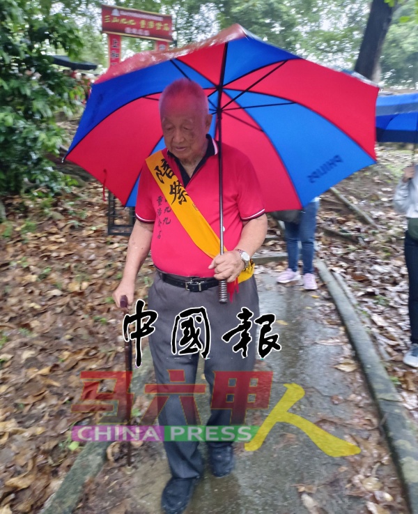 86岁的林明镜不畏风雨，登山参与“三山九九．重阳登高”活动，得知更改地点后，边撑伞边拿枴杖下山。