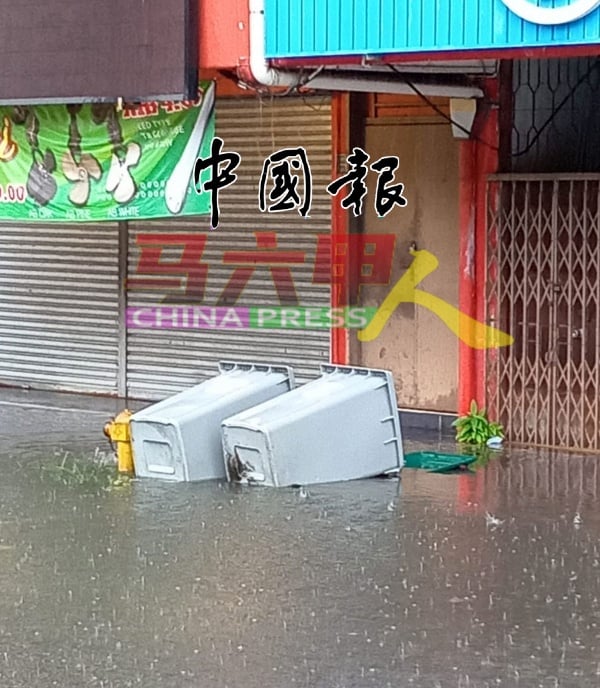 垃圾桶被雨水冲至倒下。（图谢守钦提供）