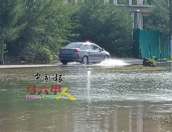 道路积满海水，车辆缓慢涉水通行。