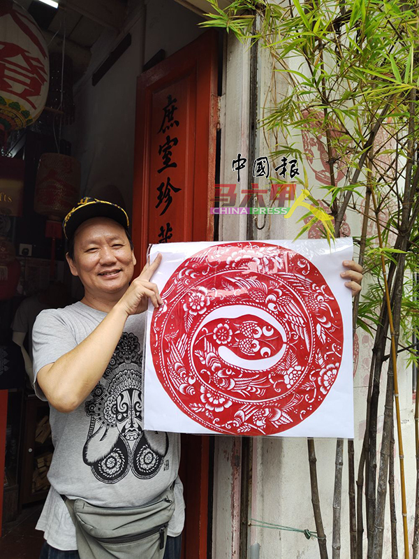 ■陈益龙展示大张蛇年剪纸,有人预订他才创作。