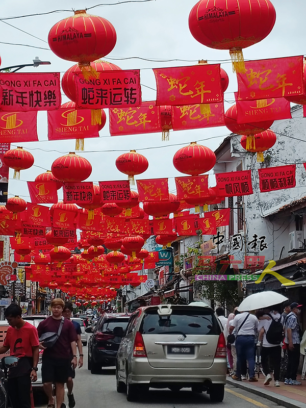 ■鸡场街上空悬挂许多印有蛇形祝福语的红色布条，年味十足。