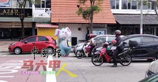 装扮者在繁忙的路中讨钱,险象环生。(档案照)