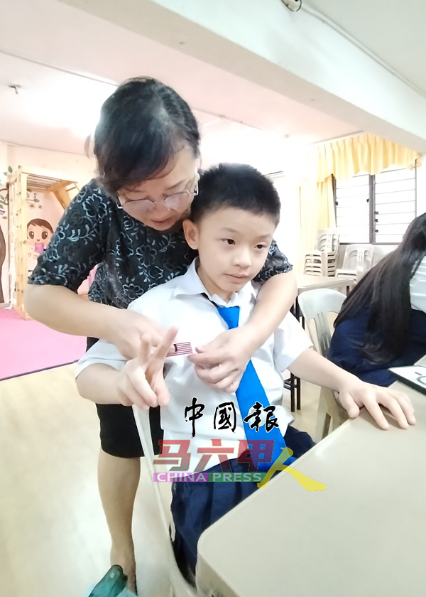 罗丽云校长协助一名学生佩戴国旗扣章。