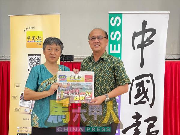 莫美蓉（左）代表马接翁武华小，从魏喜森手中接过《中国报》。