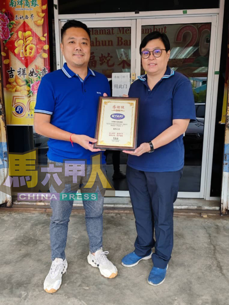 谭江菁（右起）赠送感谢状予王维光，感谢后者连续5年赞助《中国报》予招茂小学。