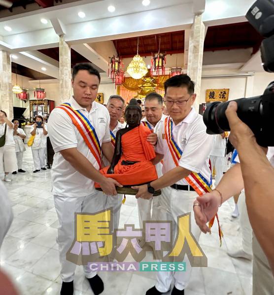 郭子毅（左起）、邱培栋、孙殿赐及林万锋，联手将释迦摩尼佛像抬上花车。