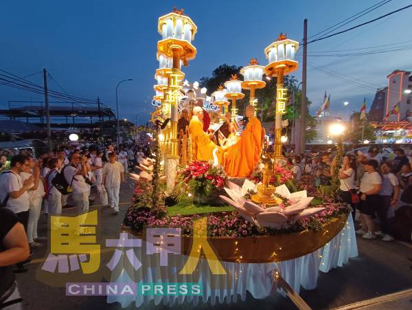 僧伽安坐花车之上，诵经祈福，佛号随风传颂。