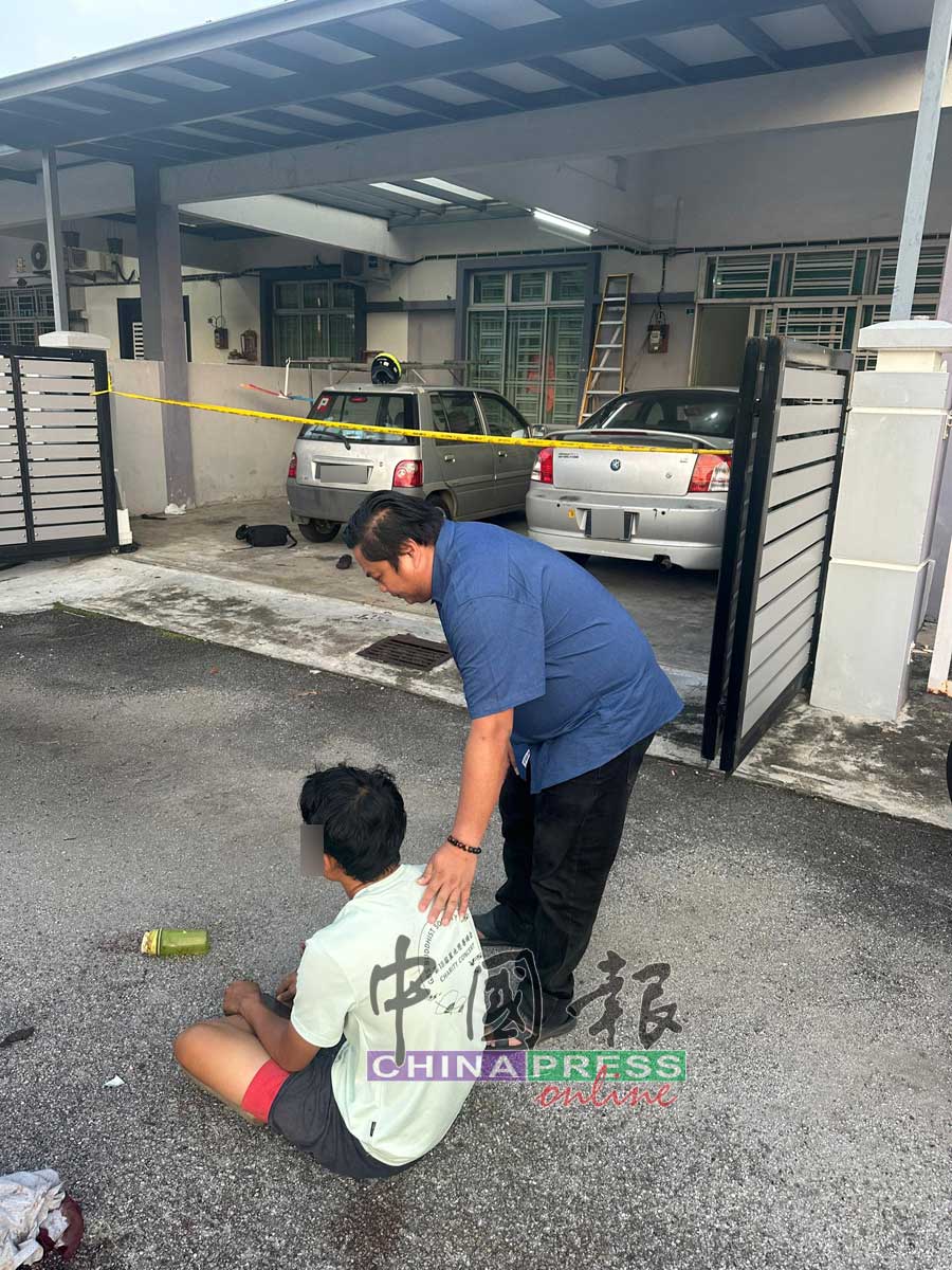 嫌犯呆坐在屋外，丹绒米雅村长林佑福在旁关心。（民众提供）