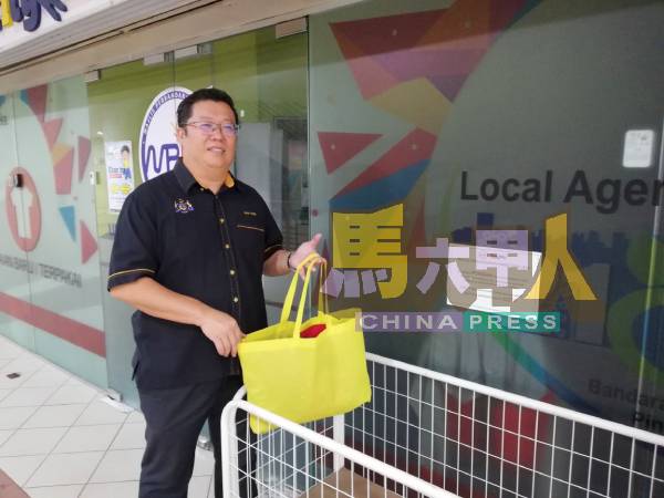 邓永森把二手衣物放在架内,待由工作人员接收和处理。
