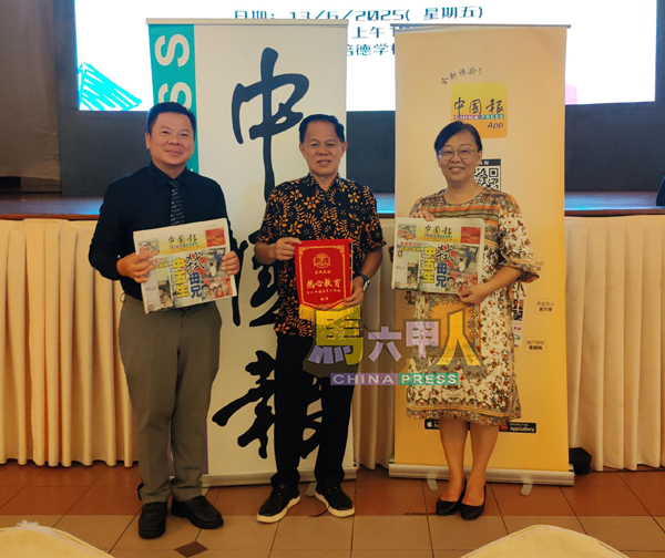 ■公教小学陈德文校长(左)及培三小学罗丽云校长(右)从朱国昇手中接过《中国报》。