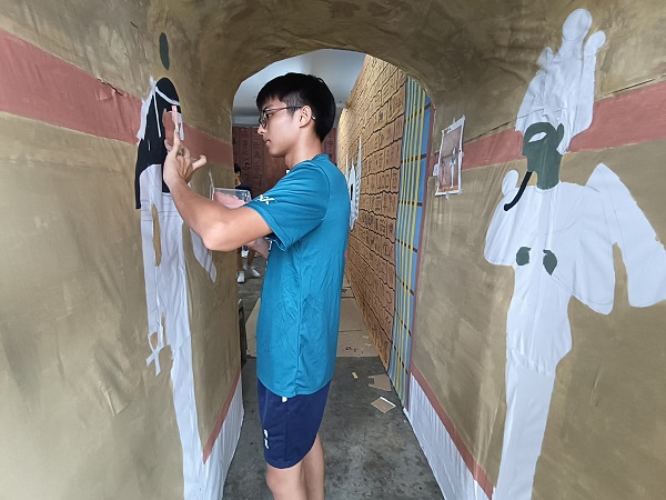 一名学生正在彩绘着门口通道的壁画。