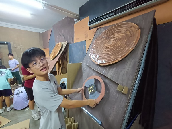 ■一名男同学正在握着方向盘,试玩“弹珠迷宫”游戏装置。