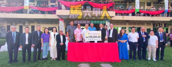 邱培栋(左9)在众人的见证下,移交10万令吉模拟支票给史进福(右8)。