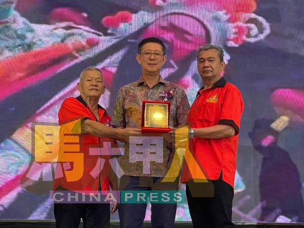 杨焕源(左2)从杨德清(左)及陈忠美(右)手中接过纪念品。