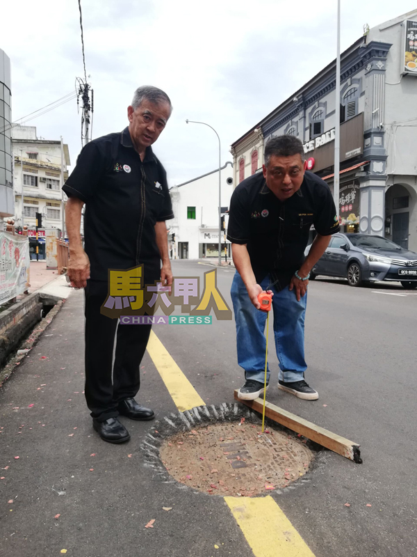 ■雷宝翔(右)测量保安宫前的路坑深度。左是陈劲源。