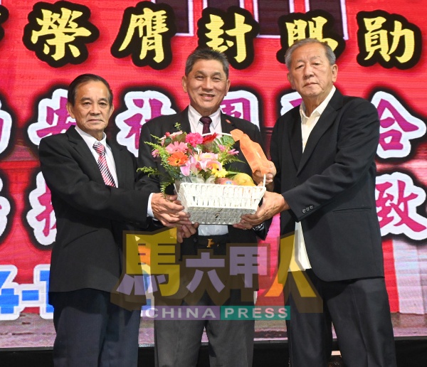 陈世源（右起）赠送水果礼篮给杨振忠。左是侯有添。