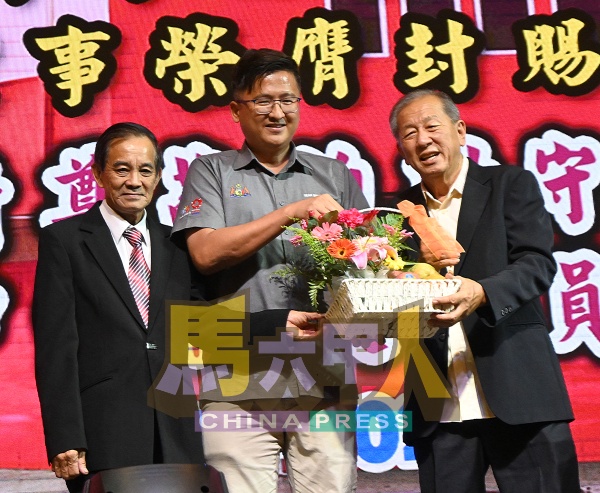 谢守钦（中）接领水果礼篮。