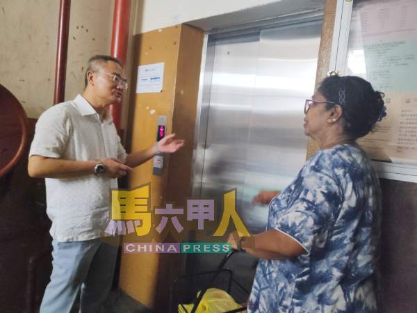 邱培栋(左)向居民了解乘塔升降机的经历。