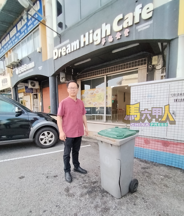 ■刘志俍察看商家共用的垃圾桶。