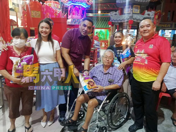 ■林朝雁（左2起）、诺希尔米和陈江荣（右），联合送福米予一名行动不便者。