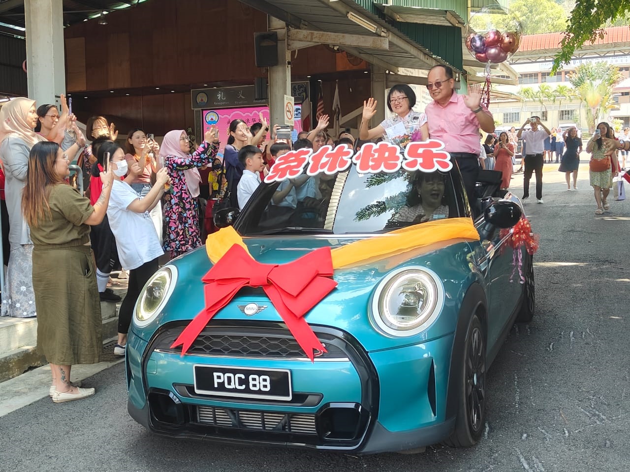 ■范美玲老师在先生戴华水的陪同下,乘坐荣休花车挥手告别武吉波浪华小,学生列队欢送。